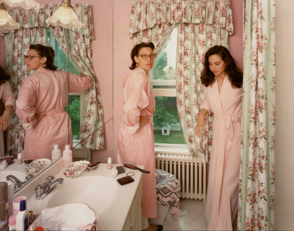 Due donne in accappatoio in un bagno, riflesse nello specchio