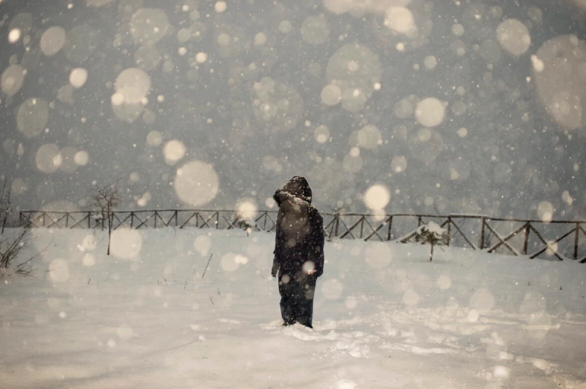 Figura sola di spalle sotto una fitta nevicata