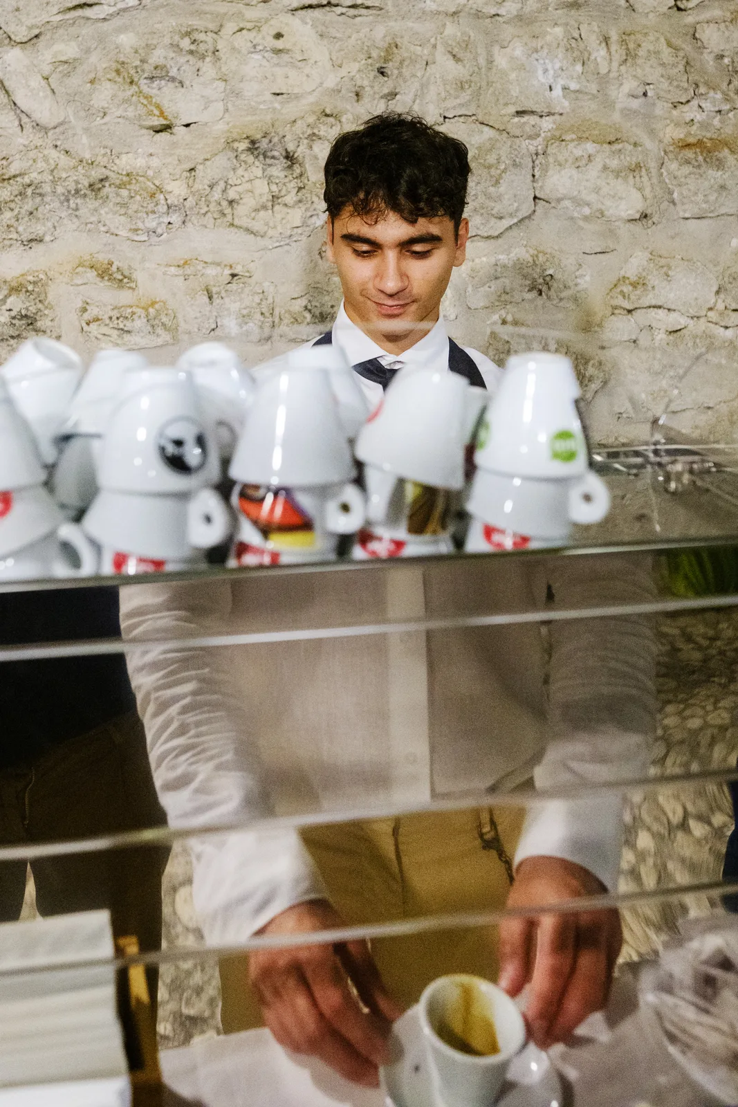 A waiter at work behind a row of white ceramic jars
